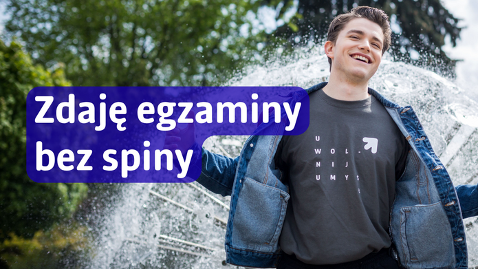 Na zdjęciu widoczny jest uśmiechnięty młody mężczyzna stojący na tle fontanny i zieleni parkowej. Ma na sobie dżinsową kurtkę i ciemną koszulkę z nadrukiem „Uniwersytet Łódzki”. W lewej części grafiki znajduje się niebieska, półprzezroczysta plansza z białym napisem: „Zdaję egzaminy bez spiny”.